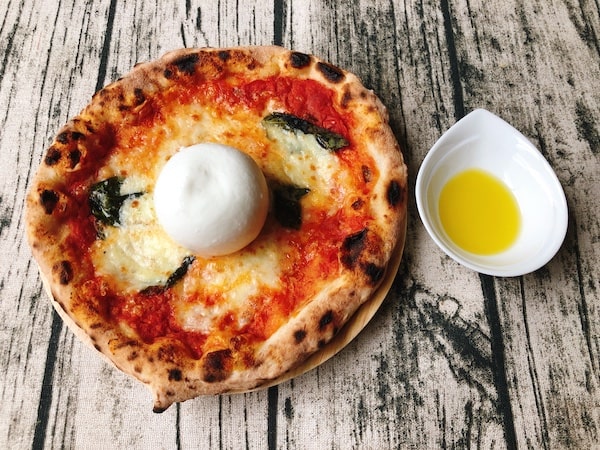 「PIZZERIA Bakka M'unica（バッカムニカ）」の冷凍ピザ「究極のマルゲリータ」にオリーブオイルをかける