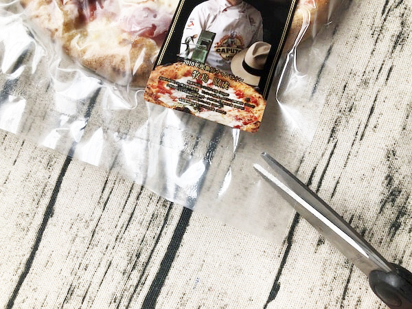 チェザリの冷凍ピザ「匠ピッツァ・マルゲリータ」の封をハサミで切る